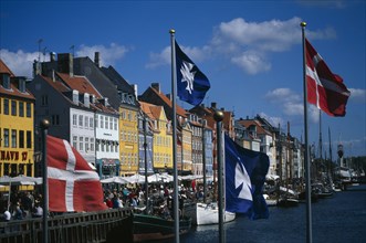 DENMARK , Zealand, Copenhagen, Nyhavn canal with colourful houses along the harbour front. Flags