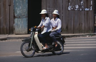 VIETNAM, South, Ho Chi Minh City, Two girls on Honda moped in downtown Ho Chi Minh City.