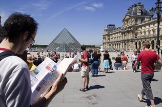 FRANCE, Ile de France, Paris, Tourists reading a guide in the square outside the pyramid entrance