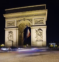 FRANCE, Ile de France, Paris, The Arc de Triomphe illuminated at night with the French tricolour