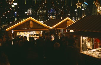 GERMANY, Berlin, Breitscheidplatz. Christmas Market. People gathered around Illuminated stalls at