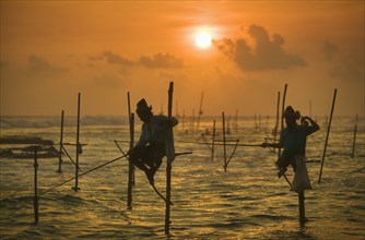 SRI LANKA, Weligama, Stilt fishermen at sunset near Weligama.