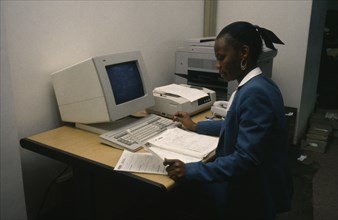 BOTSWANA, Computers, "Smartly dressed woman working on computer at office desk with printer,