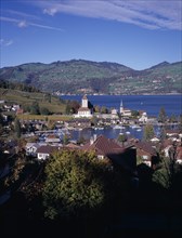 SWITZERLAND, Bernese Oberland, Spiez , View across trees and roof tops towards Spiez Village and