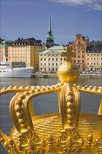 SWEDEN, Stockholm, Close-up of an ornamental crown on Skeppsholmsbron with Gamla Stan in the