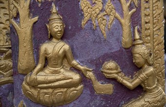 LAOS, Luang Prabang, Wat Xieng Thong.  Temple detail of gold painted relief carving on purple