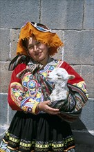 PERU, Cusco, "Lady wearing a colourful costume holding a lamb in her arms,"