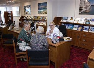 ENGLAND, West Sussex, Chichester, Male and female customer in a Travel Agents office discussing