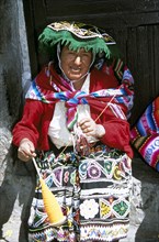 PERU, Cusco, "Lady wearing colourful traditional costume, spinning wool."