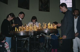 ARMENIA, Echmiadzin, Adults and children lighting candles inside church.
