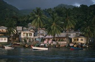 ST LUCIA, Soufriere, "Coastal housing and palm trees with colourful boats pulled up along shore.