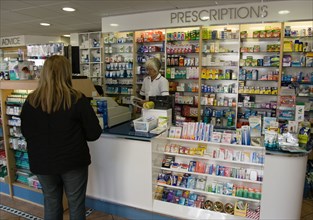 ENGLAND, East Sussex, Shoreham by sea, Interior of high street dispensing chemist  with female