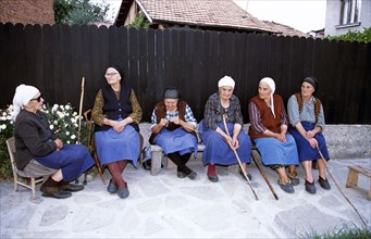 BULGARIA, Bansko, Six old ladies sitting on bench.