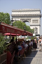 FRANCE, Ile de France, Paris, Tourists eating lunch at tables under shade in the Champs Elysees