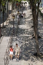 FRANCE, Ile de France, Paris, Montmartre People on the tree lined steps of the Rue Foyatier beside