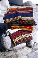 BULGARIA, Bansko, Colourful blankets on display on rocks outside gift and craft shop.