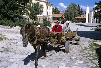 BULGARIA, Bansko, Couple on horse and cart and Paisii of Hilendar Monument.