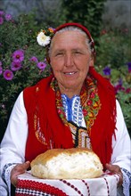 BULGARIA, Dobarsko, "Dobarski Babi Folk Group, member of folk group holding bread on plate."
