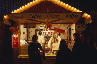 GERMANY, Berlin, "Breitscheidplatz. Christmas Market. Customers waiting at food stall illuminated