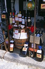 BULGARIA, Melnik., "Display of wine bottles, barrel, and containers outside shop."