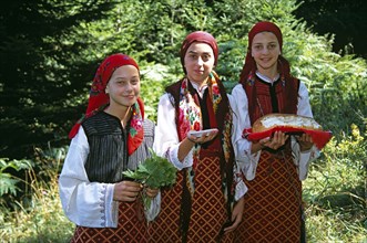 BULGARIA, Pirin Mountain, Chalin Valog, "Girls dressed in Bulgarian national costume holding bread,