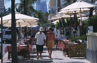 USA, Florida, Miami, South Beach. Ocean Drive. A man and woman walking past a sidewalk cafe