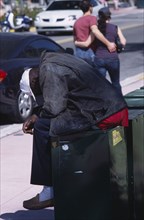 USA, Florida, Miami, South Beach. Ocean Drive. A Homeless man sitting on a news stand asleep