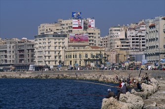 EGYPT, Nile Delta, Alexandria, Corniche Waterfront . Men and boys fishing from rocks over the sea