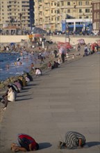 EGYPT, Nile Delta, Alexandria, Corniche Waterfront . People sitting on the edge of the promenade