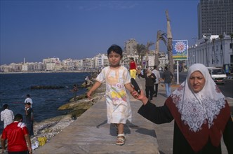 EGYPT, Nile Delta, Alexandria, Corniche Waterfront. A mother wearing an Islamic headscarf holding