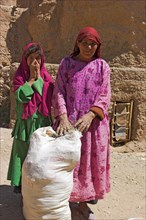 AFGHANISTAN, Bamiyan Province, Bamiyan , Local women walking back to village with sacks