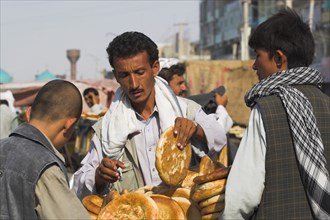 AFGHANISTAN, "Mazar-I-Sharif,", Men buying bread from street stall