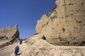 AFGHANISTAN, Ghazni, Ladies wearing burqua walk near ancient walls of Citadel destroyed during