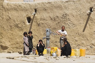 AFGHANISTAN, Ghazni, "Children fill up water containers at well near houses inside ancient walls of