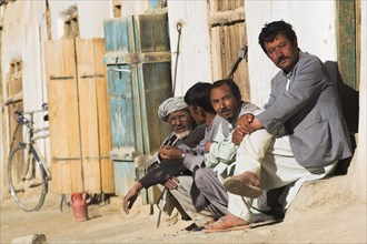 AFGHANISTAN, between Yakawlang and Daulitiar, Syadara, Men sit outside shop in early morning