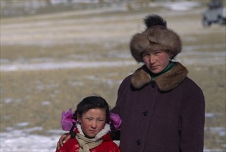 MONGOLIA, Bayan Olgii Province, Kazakh, Portrait of Kazakh woman and her daughter watching the