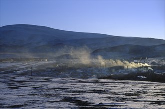MONGOLIA, Hovd Province, Erdeneburen, Drifting smoke from buildings in landscape with light