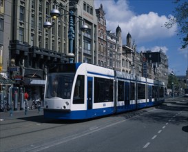 HOLLAND, Noord-Holland, Amsterdam, "Damrak.  Blue and white tram on busy street partly obscuring