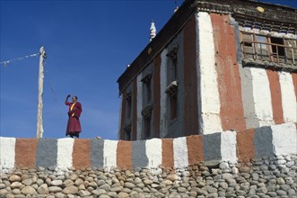 NEPAL, Mustang, Tsarang Gompa, "Tibetan Buddhist monk looking out from monastery terrace, shielding
