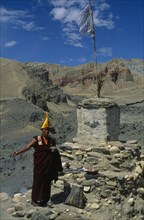 NEPAL, Mustang, Lo Manthang, Tibetan Buddhist monk making offerings of incense at a stupa during
