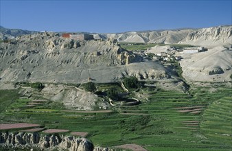 NEPAL, Mustang, Namgyal, "Namgyal Gompa on steep, eroded hilltop above cultivated fields."