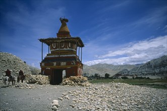 NEPAL, Mustang, Tsarang, "Old, painted stupa marking entrance to Tsarang with two horsemen