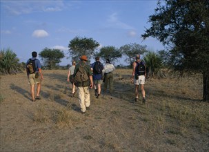 TANZANIA, Selous Game Reserve, Group of tourists on walking safari carrying rucksacks and water
