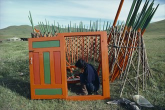 MONGOLIA, Architecture, Man painting interior framework of yurt sitting within circular lattice