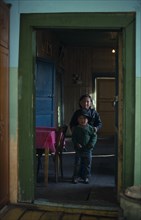 MONGOLIA, North, Children, Brother and sister standing in open doorway of home with green painted