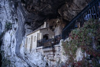 SPAIN, Asturius, Covadonga, Holy Catholic cave shrine in rock face above waterfall and pool.