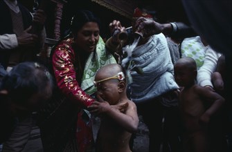 20085633 NEPAL  Patan Buddhist priests and family bless young boy with milk during his bhartavan or manhood ceremony.