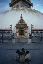 NEPAL, Kathmandu, Small group of children with baby crouched together on ground in front of