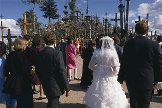 LITHUANIA, Hill of Crosses, Wedding group in front of hundreds of crosses and crucifix at ancient
