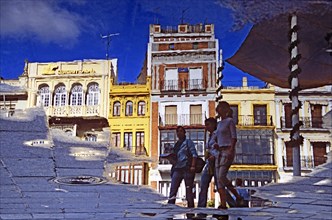 SPAIN, Andalucia, Seville, Reflection of buildings and pedestrians in Plaza de San Francisco.